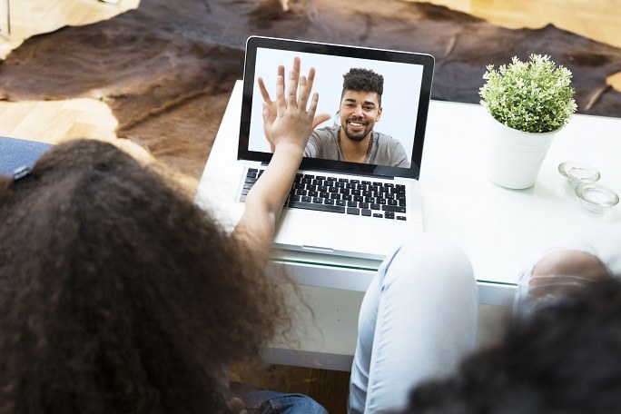 Kind im Videochat mit seinem Vater. Das Kind berührt die Hand des Vaters auf dem Bildschirm