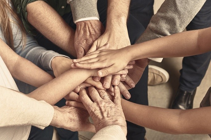 Menschen verschiedenen Alters legen ihre Hände in einem Kreis übereinander