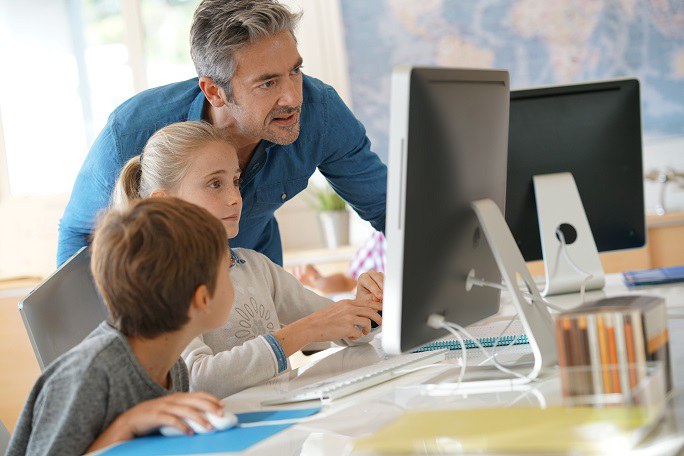 Ein Mann sitzt mit zwei Kindern vor einem Computer.
