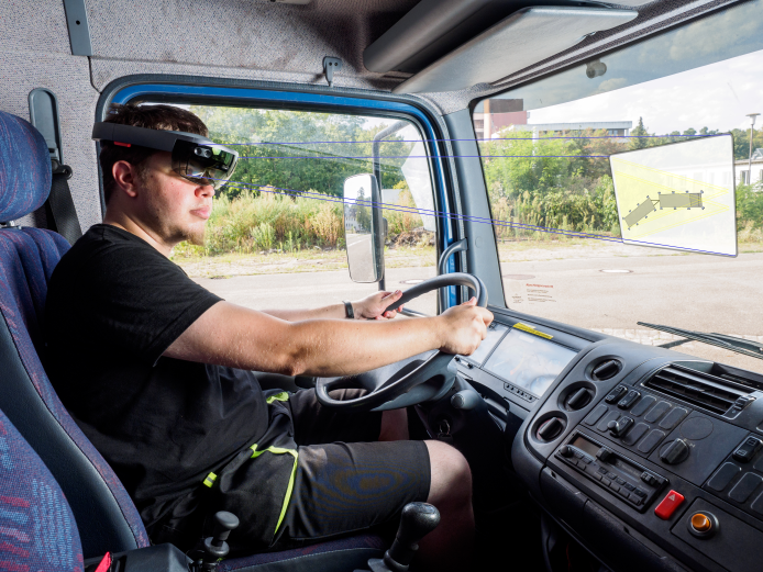 Ein unger Man fährt Auto und hat eine AR-Brille an.