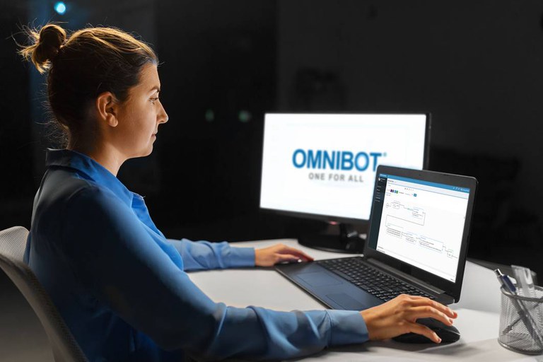 Eine Studentin sitzt vor einem Laptop. Neben dem Laptop steht ein Bildschirm, auf dem "Omnibot" steht.