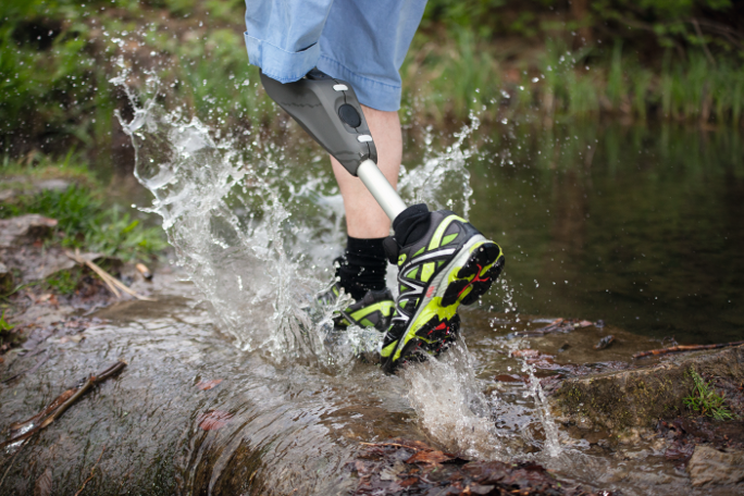 Eine Person mit einer Beinprothese die durch einen Fluss läuft. 