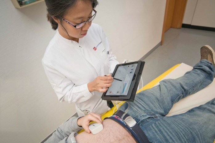 Eine Ärztin mit einem Touchpad neben einem Patienten. 