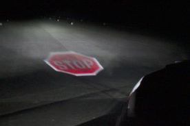 Ein Stop-Schild, welches im Dunkeln auf die Straße projiziert wird. 
