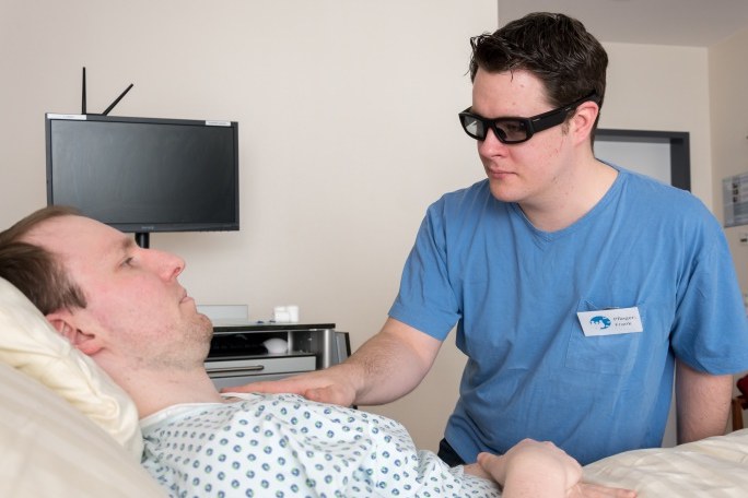 Pfleger am Krankenbett trägt eine spezielle Brille