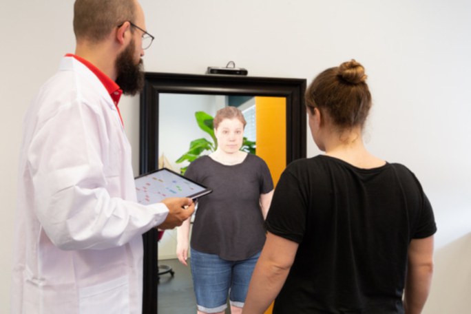 Übergewichtige Frau betrachtet in Anwesenheit eines Arztes ein virtuelles Abbild von sich